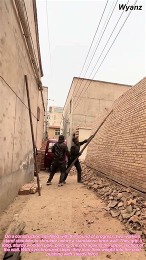 construction vlog | two workers pushing down brick wall with pole