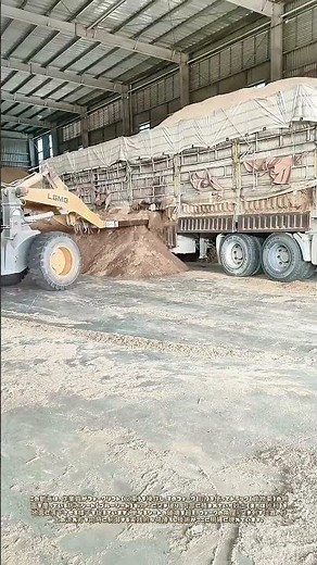 フォークリフトのフォークでトラック側面のシートを次々に破り、砂土を地面に落下させる：簡易的な荷下ろしとシート撤去の併行作業