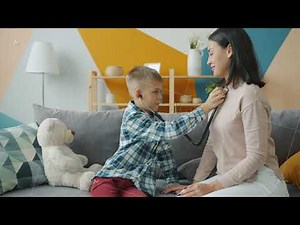 Cute little boy examining mother with stethoscope playing doctor game in apartment