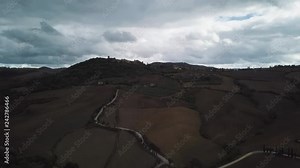 Beautiful scenery in somewhere in the Tuscany, drone flying backwards and up, revealing hills, with rainy clouds in the background.