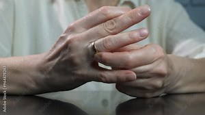 Uncertain female removing wedding ring. A view of uncertain female takes off the wedding ring from the finger during family separation.