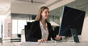Smiling businesswoman, financial analytics or marketer make research working in modern corporate office seated at desk use personal computer. Prepare report, do on-line presentation or sales analysis
