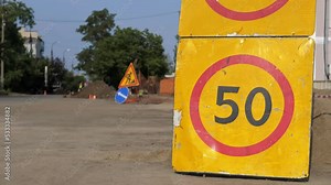 Road sign speed limit 50 km h in combination with road work ahead. Warning signs for work in progress on closed road under construction with arrow sign and traffic cone, hinders traffic in the city.