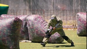 Paintball players aiming and shooting HD game slow-motion video. Man team with gun hitting on playing field venue. Sport action war battle fighting