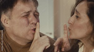 Close-up of Caucasian woman and man sneaking through house, man stepping on something and trying not to scream from pain
