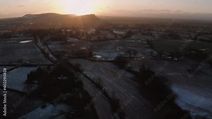 4K Aerial reveal of beautiful sunset over Cheshire, England, Winter 2020. Rural farmland, small villages and a castle on a hill in the background