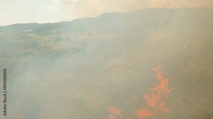 Aerial view forest fire on the slopes of hills and mountains. Forest and tropical jungle deforestation for human food farming and export. large flames from forest fire. Using fire to destroy natural Stock Video