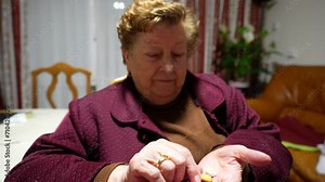 Elderly woman sorting medication at home. Intimate indoor setting, focused and concentrated