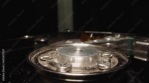Open HDD with detailed mechanism reflecting bright studio light on dark background. Electro-mechanical data storage device for computers macro