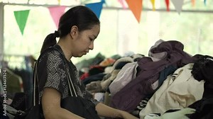 Asian mixed race woman shopping second clothes at flea market warehouse