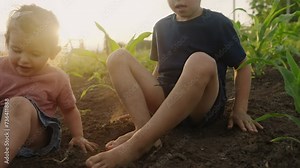Two children playing in the garden sitting with bare feet. Kid playing no shoes outdoors in rural countryside. Fun and freedom concept. Bare feet of child on