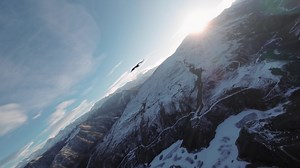Flight of a vulture in the wild nature of the highlands of the Caucasus. A bird of prey high in the sky against the backdrop of mountains and the setting sun.