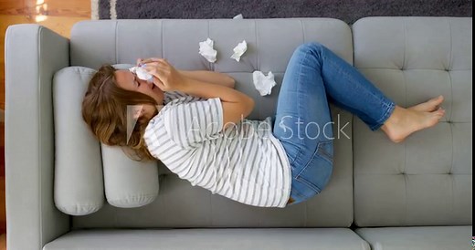 Frustrated woman covering face and crying, lying on sofa at home alone