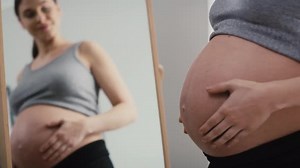 Caucasian woman in advanced pregnancy browsing herself in the mirror. Shot with RED helium camera in