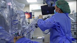 Medic turns the robotic arm input into patient’s body. Specialist changes the device position looking attentively at the screen.