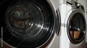 Close-up video of modern washing machines at a low angle, highlighting sleek design and chrome details in a contemporary laundry setting.