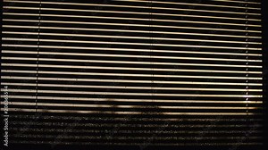 Closing blinds over window with desperate view 4K. Long shot of wet window in focus on a rainy day while putting down blinds blocking the view.