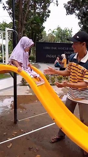 Playground Fun: Child Sliding with Adult Guidance