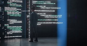 Portrait of Young Woman Working on Laptop Computer, Looking at Big Digital Screen Displaying Back-end Code Lines. Professional Programmer Developing a Big Data Interface Software Project