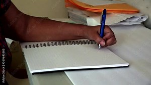Black woman taking notes in a notebook. Left Handed. Hands Only. Stock Video