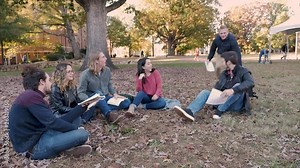Male college student pulls a backpack from under one of his classmates