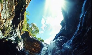 A view of a waterfall from below, looking up to the sky.
