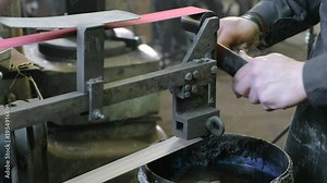 Grinding billets of metal knife on a belt-grinding machine. Close-up of a man's hand.