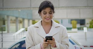 Close Up Slow Motion Successful And Cheerful Young Brunette Caucasian Woman Using Smartphone in City Financial District. She Is Sending Messages, Checking Mails, Chats Or The News Online.