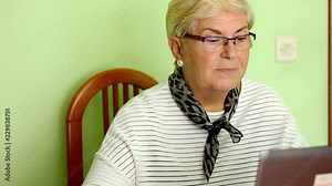Senior blonde woman using laptop at home. Older lady reading computer screen sitting in living room. Elderly education, internet communication, technology concepts