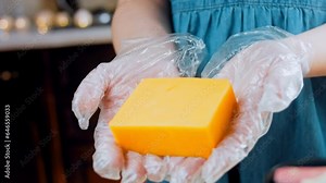 Cutting cheddar on board close-up. Hard cheese, fresh cheddar