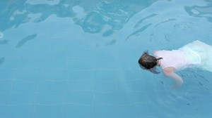 drowned woman body drifting in a swimming pool facing down