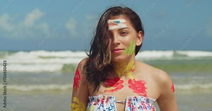 A girl on a Caribbean beach, adorned in body paint and a bikini, savors the sunny weather close up