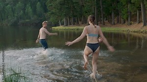 best friends jumping in lake at sunset taking off clothes splashing water enjoying playful game young people on summer vacation adventure