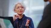 A senior businesswoman with glasses and short white hair confidently...