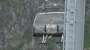 Bored young woman riding a cable car in mountains
