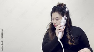 Woman using a curling iron to style her hair, creating beautiful curls and waves for a glamorous look