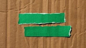 Important announcement message writing on ripped torn green paper pieces on cardboard background