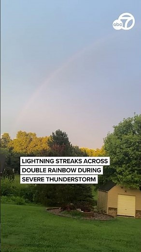Lightning streaks across double rainbow during severe thunderstorm