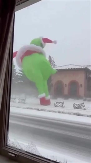 A humorous and giant inflatable Grinch dressed as Santa Claus swaying in the wind during a snowstorm | VibeNest