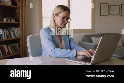Busy young freelance professional woman working from home, reviewing legal documents, typing on laptop, analyzing paper financial reports, touching chin, thinking on task, finding solution Stock Video Footage - Alamy