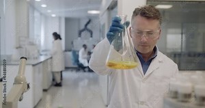 Male scientist looking at conical flask sample in a laboratory