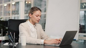 Smiling businesswoman working on laptop computer at office place. Female professional typing on laptop keyboard makes a commercial offer to potential customers. Portrait of positive business woman.
