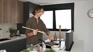 Asian young man testing chinese or taiwanese tomato scrambled eggs and burning his tongue at kitchen.