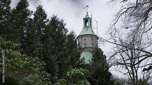 Looking at the church tower hidden with copper roof behind trees of an old castle in Germany