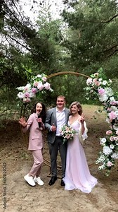 Beautiful and cheerful bride and groom pose for a photograph during an outdoor wedding ceremony in the forest. slow motion,vertical video Stock Video
