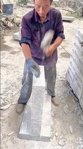 Skilled worker chiseling and shaping a solid stone block with precise hammer strikes