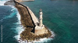 Aerial drone video of iconic Venetian lighthouse in the entrance of picturesque old port of Chania with beautiful colours, Crete island, Greece. Lighthouse in Chania. Lighthouse of the city of Chania.