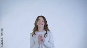 Happy young girl jumps and claps her hands at camera