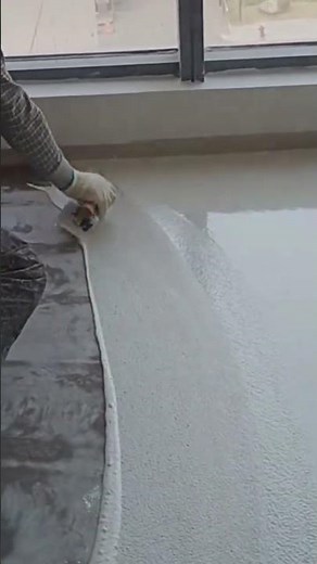 applying white self leveling epoxy to a grey concrete floor using a squeegee for a smooth coating