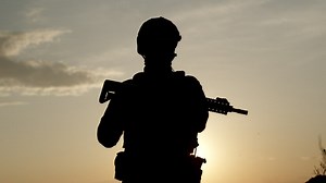 Silhouette of an armed soldier looking into the distance  - Free Stock Video